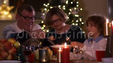 新年的背景下，一家人在烛光`庆祝圣诞节。 爷爷把沙拉放在他的